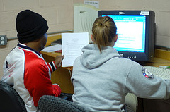 Two students write a resume at a computer