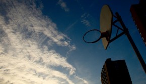 A basketball hoop is sillouettted against a mackerel sky