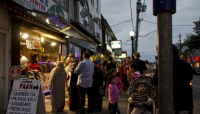 A crowd gathers around a treat seller in Toronto's Little India at twilight