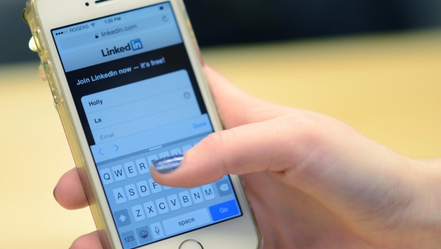 Student holding cellphone typing information into LinkedIn app