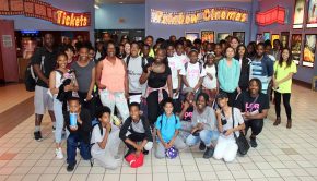 Youth group stands outside cinema posing for a photo.